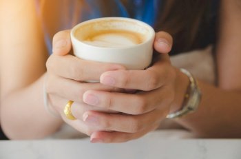 female hand holding white coffee cup
