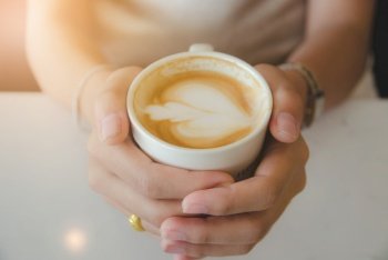 close up female hand holding white coffee cup