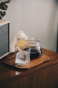 coffee drip in glass with cube ice on wooden plate