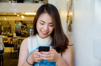 asian girl holding phone in coffee cafe with smile face