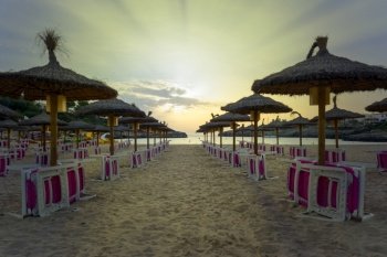 Panoramic photography, Rows of umbrellas and sunbeds for sunbathing next to the beach at sunset in Majorca island. cala marsal beach, beaches of mallorca, spain, with rows of umbrellas and hammocks, ready for tourists,vacation tourism concept