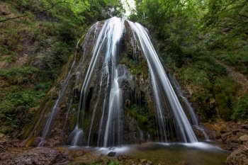 A cool waterfall in a mountain forest in the Italian Alps