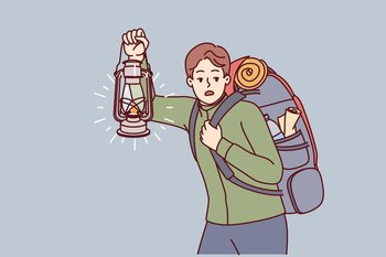 Man is engaged in hiking and carries large backpack on back, holding kerosene lantern to light way in dark. Frightened guy hears rustle in bushes and looks around while hiking in forest. Man is engaged in hiking and carries large backpack on back, holding kerosene lantern to light way in dark