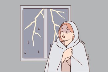 Woman was frightened by lightning and storm outside window wrapped herself in blanket because of fear of thunderstorm. GIrl suffers from phobia caused by bad weather and night hurricane. Woman was frightened by lightning and storm outside window wrapped herself in blanket