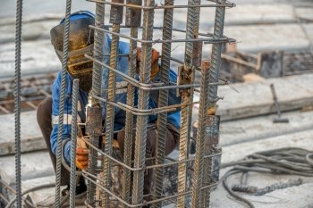 A welder on the construction site makes a metal structure for pouring concrete. Welder on the construction site makes a metal structure for pouring concrete
