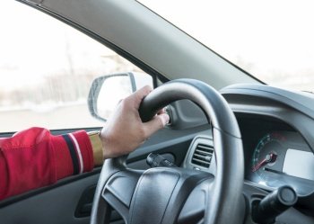 men’s hand with a watch on the steering wheel of a modern car. hand on the steering wheel