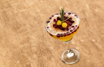 yellow fruit cocktail with berries on light brown background. smoothie on a brown background