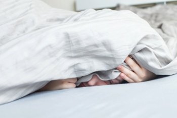 boy in the bed in the morning. the child lies and covers his face with a blanket. boy in the bed in the morning. child lies and covers his face with a blanket