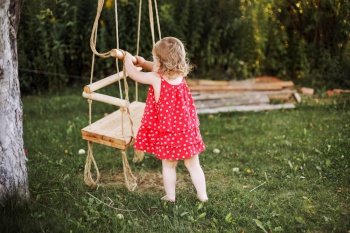girl in the garden playing with swings. baby playing in the garden alone