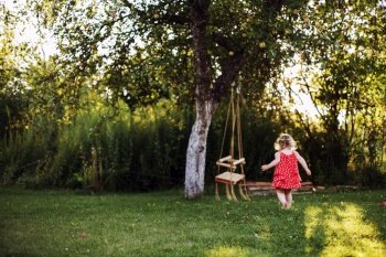 girl in the garden playing with swings. baby playing in the garden alone