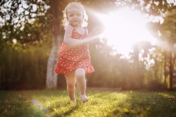 happy baby smiling. little girl running at sunset