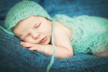 newborn baby sleeping sweetly on a blue background. newborn baby sleeping sweetly on a blue rug in blue cap