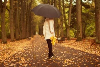 woman with an umbrella walks in autumn park