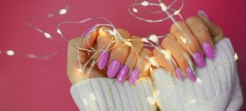 Cozy nails with winter manicure with snowflakes and lights on purple background.. Cozy nails with winter manicure with snowflakes and lights on purple background