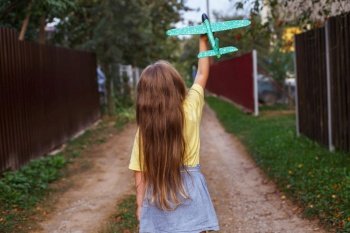 Happy child girl with long blond hair playing with toy airplane outdoor.. Happy child girl with long blond hair playing with toy airplane outdoor at sunset