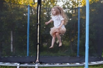 a Little child girl jumping on the trampoline in the back yard. Little child girl jumping on the trampoline in the back yard
