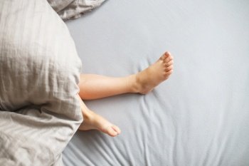 child sleep in the bed. baby’s feet stick out from under the blanket