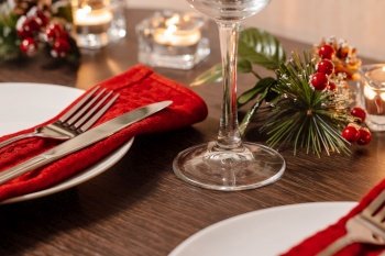 Christmas table setting. Plate and cutlery on red napkin. Candles burning on table on Christmas Eve. Preparing for a festive dinner.. Christmas table setting. Plate and cutlery on red napkin. Candles burning on table on Christmas Eve. Preparing for festive dinner.