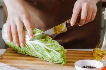 Young woman preparing diet salad and slicing Chinese cabbage. Healthy food concept. Cooking at home.. Young woman preparing diet salad and slicing Chinese cabbage. Cooking at home.