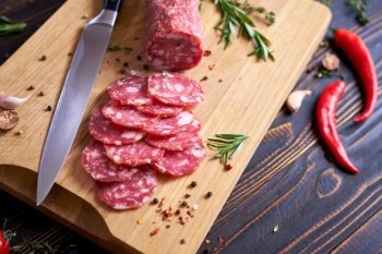 Traditional salami sausage on wooden cutting board with spices.. Traditional salami sausage on wooden cutting board with spices