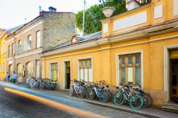 Tallinn, Estonia. Bicycles Rental Bikes Parking Near Old House In Old Part Town In Summer Evening. Bicycle Tourism.. Tallinn, Estonia. Bicycles Rental Bikes Parking Near Old House In Old Part Town. Bicycle Tourism