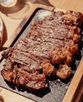 Grilled ribeye steak on wooden board. Grilled meat with sauce.
