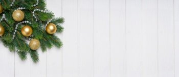 Christmas tree branch decorated with golden balls on white wooden background. Top view, flat lay with copy space, banner, header, New Year background. Christmas background with fir tree and decor. Top view, flat lay with copy space