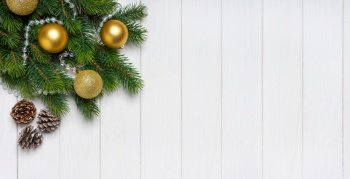 Christmas tree branch decorated with golden balls and fir cones with in craft paper on white wooden background. Top view, flat lay with copy space, banner, header, New Year background