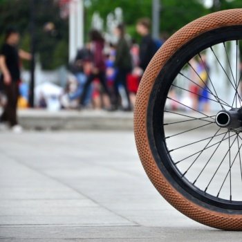A BMX bike wheel against the backdrop of a blurred street with cycling riders. Extreme Sports Concept