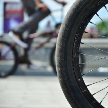 A BMX bike wheel against the backdrop of a blurred street with cycling riders. Extreme Sports Concept