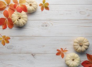 Thanksgiving season still life with small pumpkins and fall leaves over rustic wooden background