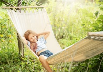 A little girl rests in a hammock and eats cherries in the summer.  Summer in the village. 