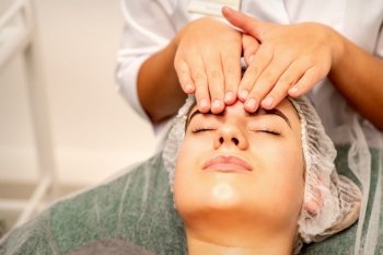 Head massage. Beautiful caucasian young white woman receiving a head and forehead massage with closed eyes in a spa salon. Head massage. Beautiful caucasian young white woman receiving a head and forehead massage with closed eyes in a spa salon.