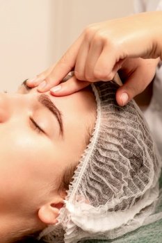 Beautiful caucasian young woman receiving a facial massage with closed eyes in spa salon, close up. Relaxing treatment concept. Beautiful caucasian young woman receiving a facial massage with closed eyes in spa salon, close up. Relaxing treatment concept.