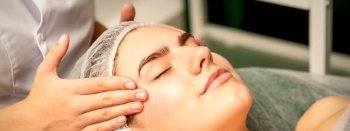 Head massage. Beautiful caucasian young white woman receiving a head and forehead massage with closed eyes in a spa salon. Head massage. Beautiful caucasian young white woman receiving a head and forehead massage with closed eyes in a spa salon.
