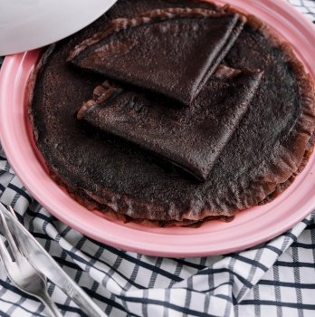 Chocolate pancake on pink plate close up