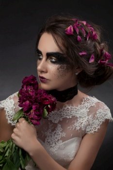 bride in a wedding dress with a black gothic makeup and dried flowers
