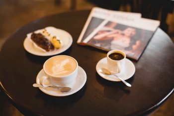close up a mug of fragrant cappuccino and a sweet dessert and a magazine on the table