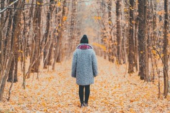Young woman standing alone along trail in autumn forest. Back view. Travel, freedom, nature concept. Young woman standing alone along trail in autumn forest. Back view. Travel, freedom, nature concept.