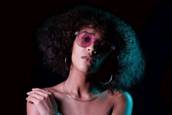 Portrait of young alluring mixed race girl in neon light. Fashion, glamour, model concept. Seductive woman with make-up and transparent glasses posing in dark room at night. Portrait of young alluring mixed race girl in neon light. Fashion, glamour, model concept. Seductive woman with make-up and transparent glasses posing in dark room at night.