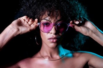 Alluring unusual girl with curly afro hair corrects her glasses. Sexy woman with perfect makeup looking at camera and smiling. Glamour, fashion concept. Alluring unusual girl with curly afro hair corrects her glasses. Sexy woman with perfect makeup looking at camera and smiling. Glamour, fashion concept.