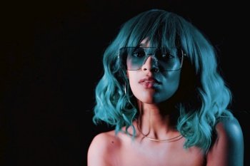 Charming unusual girl with blue hairstyle and glasses. Sexy woman with perfect makeup and wig looking at camera and smiling. Glamour, fashion concept. Charming unusual girl with blue hairstyle and glasses. Sexy woman with perfect makeup and wig looking at camera and smiling. Glamour, fashion concept.