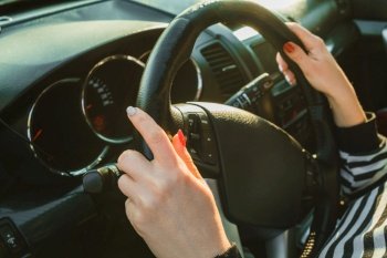Female hands on black steering wheel of modern car. Automobile saloon. Woman driving on road. . High quality photo. Female hands on black steering wheel of modern car. Automobile saloon. Woman driving on road. 