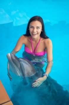 Portrait of young happy woman swimming with dolphin in pool. Portrait of young woman swimming with dolphin in pool