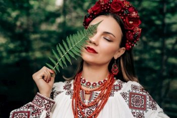 Portrait of ukrainian woman with fern in Carpathian mountains forest. She in in traditional ukrainian wreath, national dress - vyshyvanka, ancient coral beads.. Portrait of ukrainian woman with fern on Carpathian mountains forest background