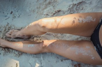 Close up lady with naked legs concept photo. Sand trace on body. Side view photography with sandy coast on background. High quality picture for wallpaper, travel blog, magazine, article. Close up lady with naked legs concept photo