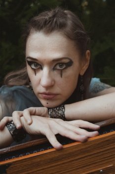 Close up staring woman with druid makeup portrait picture. Witchcore aesthetic. Closeup front view photography with blurred background. High quality photo for ads, travel blog, magazine, article. Close up staring woman with druid makeup portrait picture
