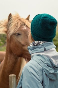 Close up woman with chestnut horse concept photo. Animals care. Rear view photography with farmland on background. High quality picture for wallpaper, travel blog, magazine, article. Close up woman with chestnut horse concept photo