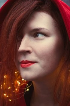 Close up happy woman with red lipstick and fairy lights portrait picture. Closeup side view photography with blurry background. High quality photo for ads, travel blog, magazine, article. Close up happy woman with red lipstick and fairy lights portrait picture