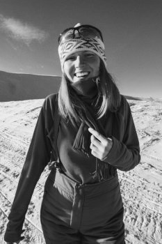 Close up joyful woman on snowy mountain monochrome portrait picture. Closeup front view photography with clear sky on background. High quality photo for ads, travel blog, magazine, article. Close up joyful woman on snowy mountain monochrome portrait picture